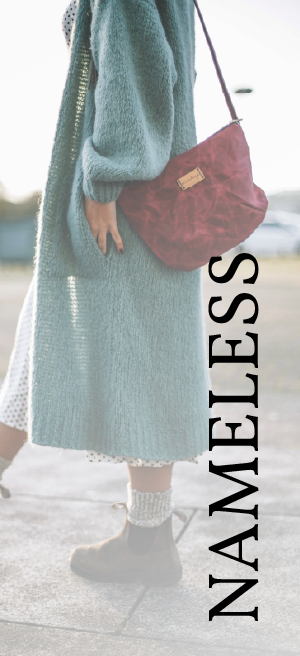 a woman wearing a long sweater and a red purse